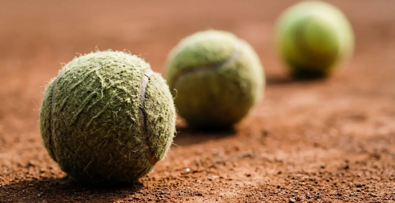 Détails macro de balles de tennis sur terre battue symbolisant différentes stratégies de jeu