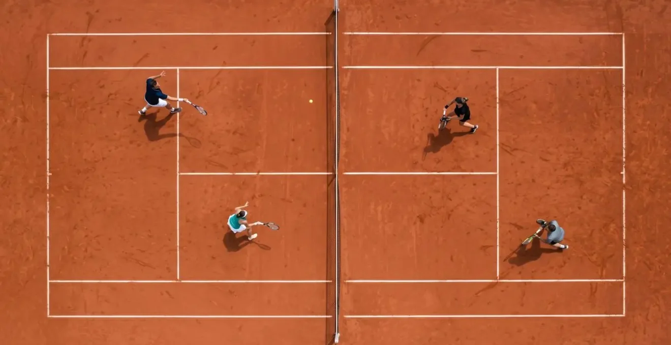 Vue en plongée d'un match de double de tennis montrant le positionnement tactique des joueurs