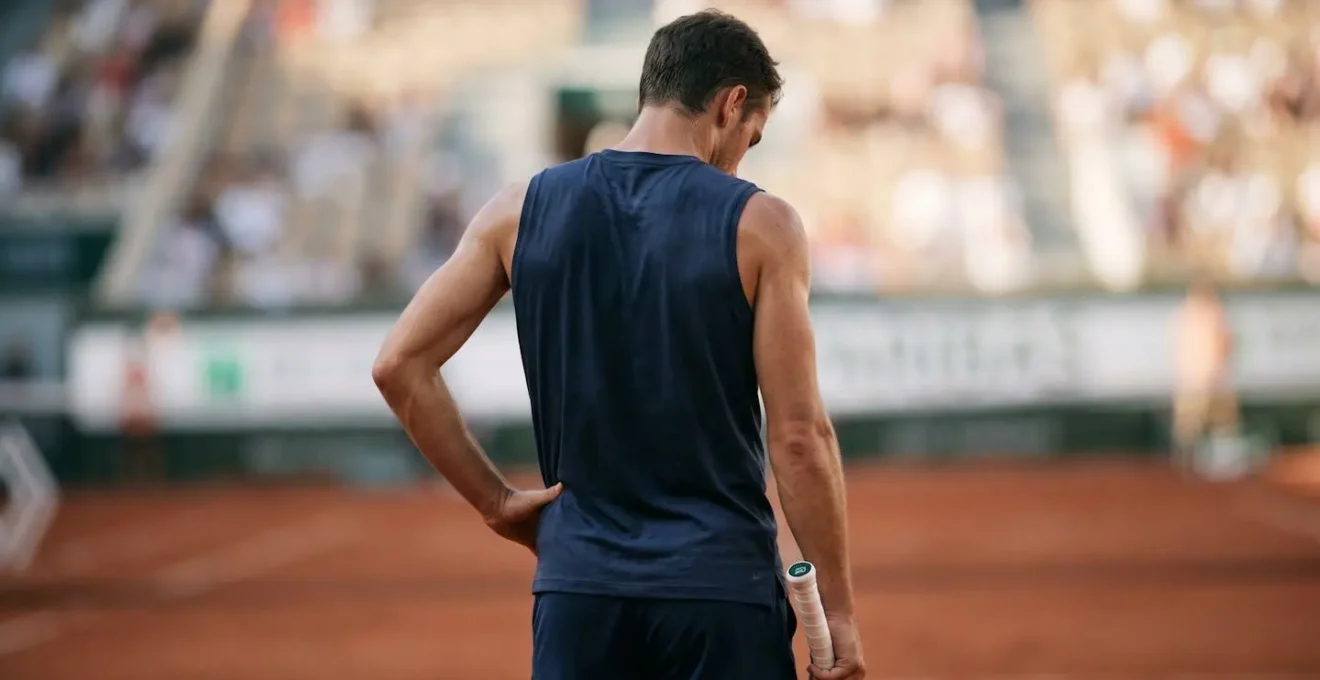 Portrait rapproché d'un joueur de tennis professionnel en plein effort, montrant l'intensité mentale et la fatigue physique