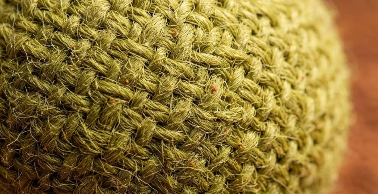 Gros plan macro sur le tissage serré du feutre d'une balle de tennis terre battue montrant sa résistance à l'humidité