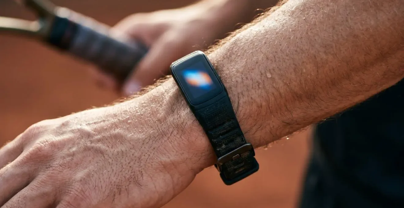 Gros plan sur un poignet portant une montre connectée montrant la fréquence cardiaque pendant un entraînement de tennis progressif